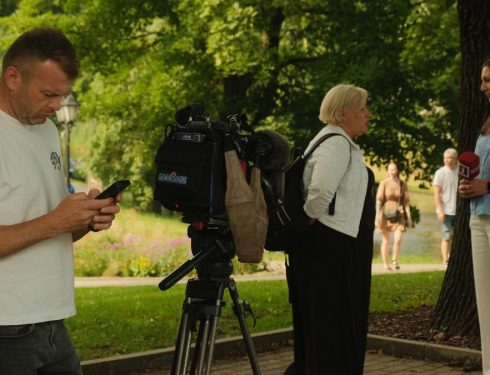 News crew conducting outdoor interview with professional camera setup in a lush park.